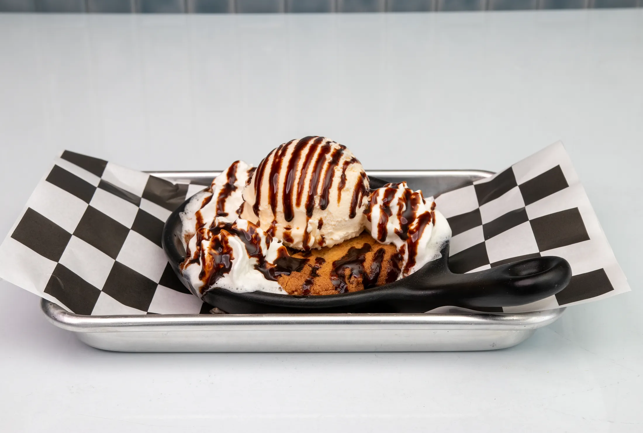 Warm chocolate chip skillet cookie with vanilla drizzle at The Rusty Roost